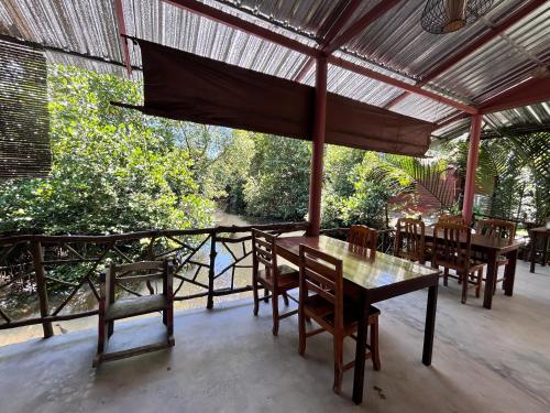 a dining room with a table and chairs on a porch at Suchanaree@Laemngop in Trat