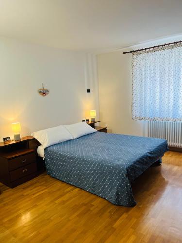 a bedroom with a bed with a blue comforter at Appartamento Al Lago in Chiesa