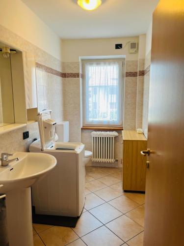een badkamer met een wastafel, een toilet en een raam bij Appartamento Al Lago in Chiesa