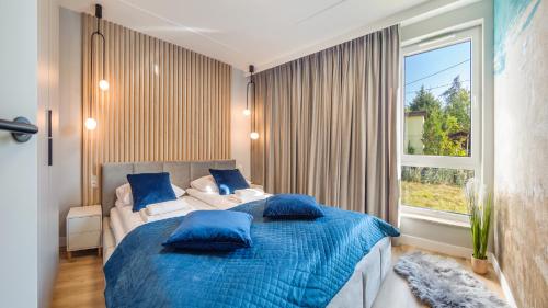 sypialnia z łóżkiem z niebieskimi poduszkami i oknem w obiekcie Apartamenty Sun & Snow Baltic Line w Gdańsku