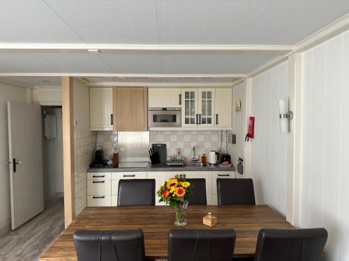 una cocina con una mesa de madera con sillas y un jarrón de flores en Zaandam Cottage Centre - Zaanse Schans Amsterdam, en Zaandam