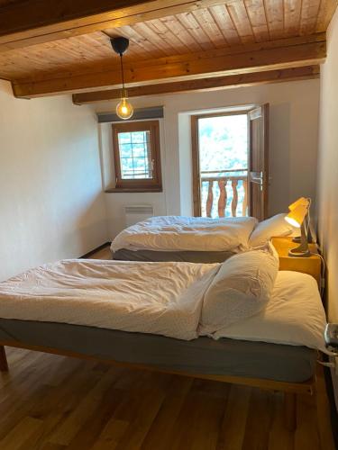 two beds in a room with two windows at Casa nonna Domenica in Brontallo