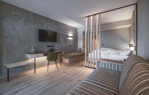 a bedroom with a bed and a desk and a bed sidx sidx sidx at Kronplatz-Resort Berghotel Zirm in Valdaora