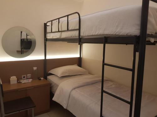 a bedroom with two bunk beds and a mirror at Aurora House Surabaya in Wijung