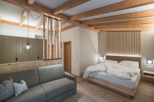 - une chambre avec un lit et un canapé dans l'établissement Kronplatz-Resort Berghotel Zirm, à Valdaora