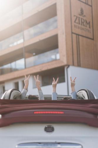a group of people with their hands up in a car at Kronplatz-Resort Berghotel Zirm in Valdaora