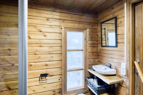 baño con paredes de madera, lavabo y ventana en Pinetree Cottages Blue Cabin en Pyhäranta