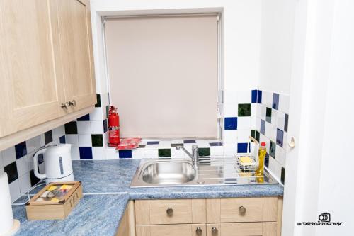 una pequeña cocina con fregadero y ventana en Cosy home with private parking en Bloxwich