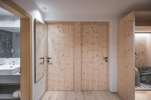 uma casa de banho com portas de correr em madeira num quarto em Kronplatz-Resort Berghotel Zirm em Valdaora