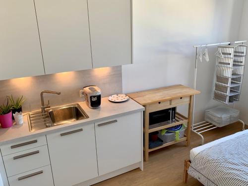 a kitchen with white cabinets and a sink and a bed at host.salzburg in Salzburg