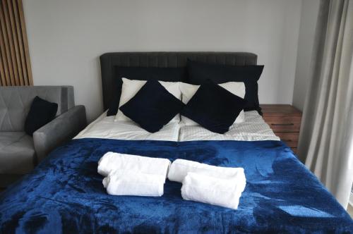 a blue and white bed with black and white pillows at JM Apartament in Ustronie Morskie