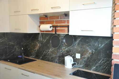 a kitchen with white cabinets and marble counter tops at JM Apartament in Ustronie Morskie