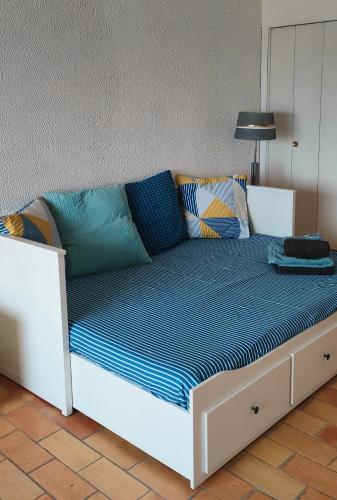 Una cama blanca con sábanas azules y almohadas. en Studio vue mer, en Bandol