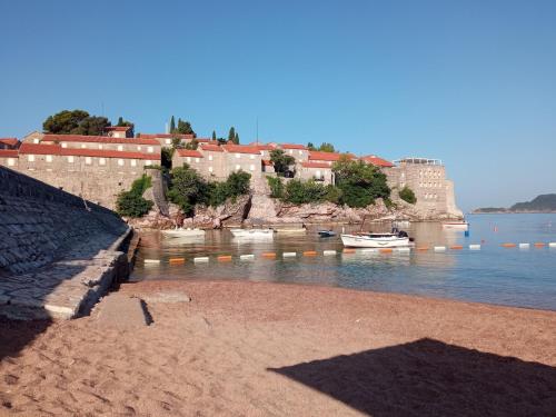 a beach with buildings and boats in the water at Apartmani Dačo in Sveti Stefan