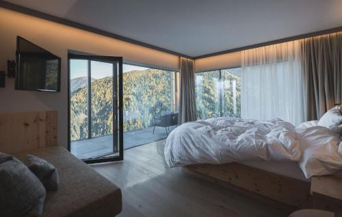 a bedroom with a bed and a large window at Kronplatz-Resort Berghotel Zirm in Valdaora