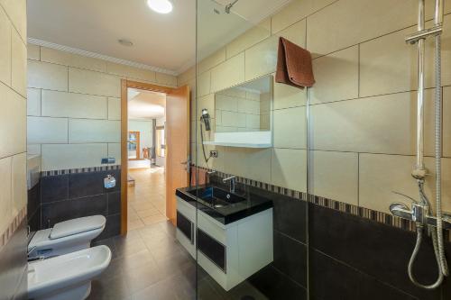 a bathroom with a sink and a toilet and a shower at Villas Camelot by LIVVO in Playa Blanca