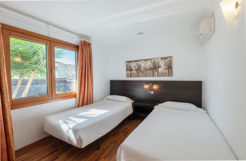 two beds in a room with a window at Villas Camelot by LIVVO in Playa Blanca