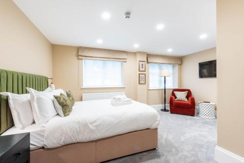 a bedroom with a large bed and a red chair at Old Abbey House in Abingdon