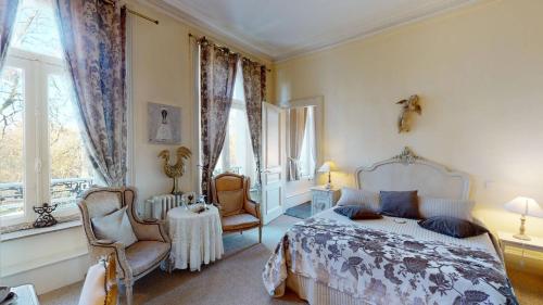a bedroom with a bed and a chair and windows at Château "Le Castel des Anges" in Wailly-Beaucamp