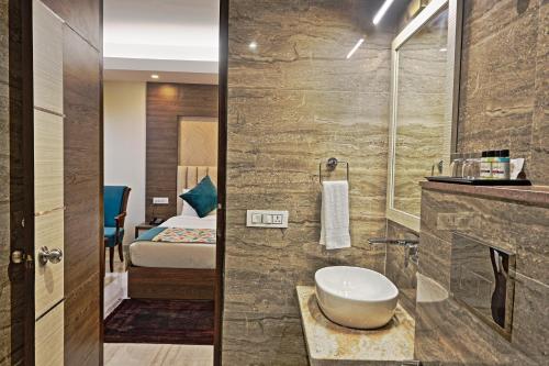 a bathroom with a sink and a room with a bed at Cardinal Express Oxmo in New Delhi