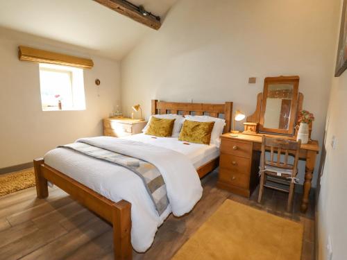 a bedroom with a bed and a desk and a mirror at The Hayloft in Holmfirth