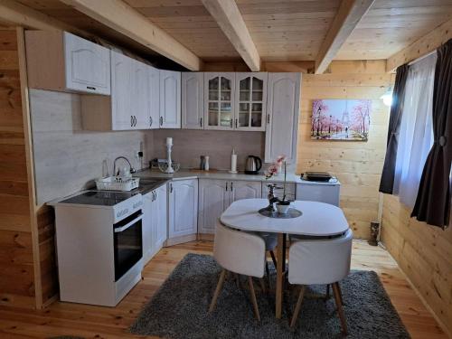 uma cozinha com armários brancos e uma mesa e cadeiras em Olive & sea, Luxury two bedrooms cabin for 8 em Ulcinj