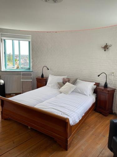 a bedroom with a bed with white sheets and a window at Torenkamer op de vijfde verdieping van de watertoren van Strijen in Strijen