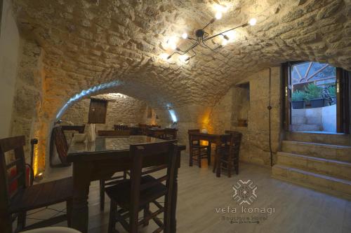 聖露法的住宿－Vefa Konagı Boutique Otel，一间设有石墙和桌椅的用餐室
