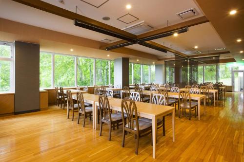 a banquet hall with wooden tables and chairs at Niseko Hot Spring Ikoino Yuyado Iroha in Niseko