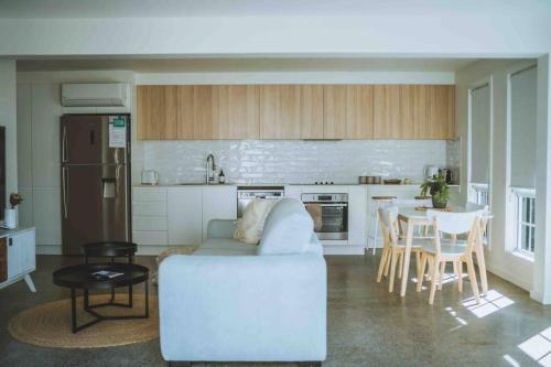 ein Wohnzimmer mit einem weißen Sofa und einer Küche in der Unterkunft Hampton Bliss Kiama in Kiama Downs