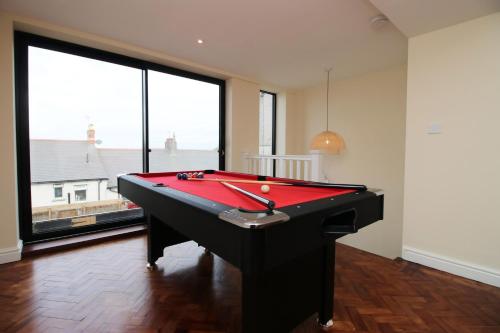 a red pool table in a room with large windows at LUXURY 4 Bedroom 4 Ensuite Home in Penarth (Pool Table Games Room & BBQ Garden) with Sea Views in Cardiff