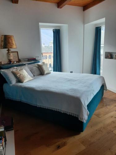 1 dormitorio con 1 cama grande con sábanas azules y ventana en Gelsomino House, en Vogogna