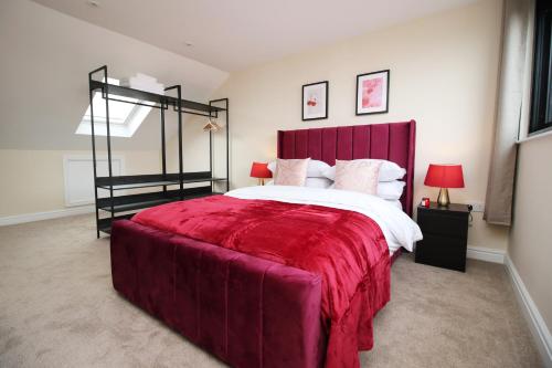 sypialnia z dużym łóżkiem z czerwonym zagłówkiem w obiekcie LUXURY 4 Bedroom 4 Ensuite Home in Penarth (Pool Table Games Room & BBQ Garden) with Sea Views w Cardiff