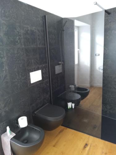 Baño negro con 2 aseos y lavamanos en Gelsomino House, en Vogogna