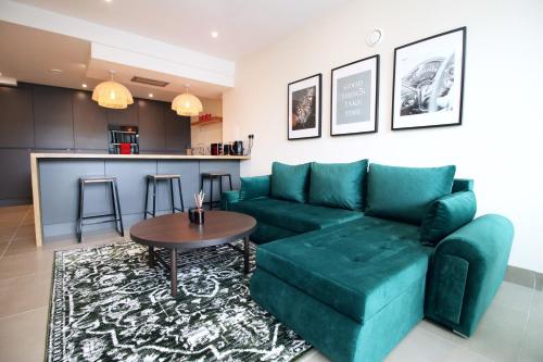 a living room with a green couch and a table at LUXURY 4 Bedroom 4 Ensuite Home in Penarth (Pool Table Games Room & BBQ Garden) with Sea Views in Cardiff