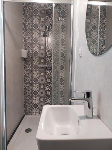 a bathroom with a sink and a shower with a mirror at COMFORT Suites VELIKA GORICA in Velika Gorica