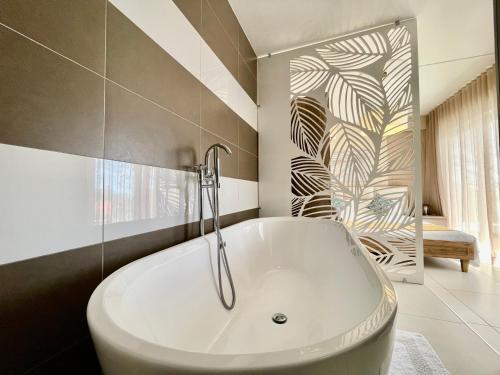 a white bath tub in a bathroom with a mural at Duplex - piscine, jacuzzi & vues in Flic-en-Flac