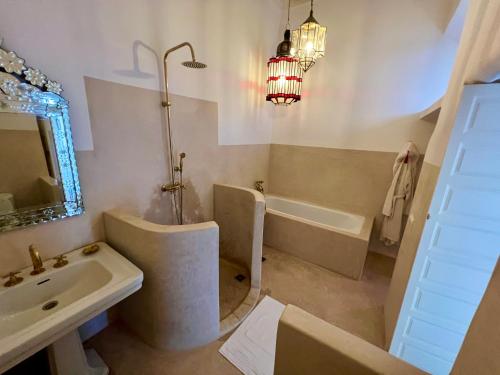 a bathroom with a sink and a bath tub and a sink at Riad Tizwa Marrakech in Marrakech