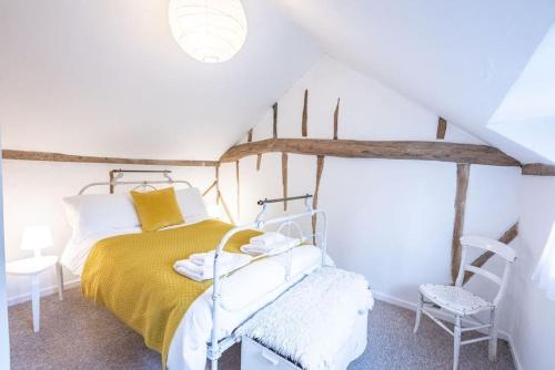 une chambre avec un lit jaune et une chaise dans l'établissement Lilac Cottage, Wenhaston, à Halesworth