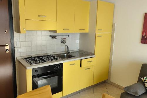 eine gelbe Küche mit Herd und Spüle in der Unterkunft PomeziaCity Apartment in Pomezia