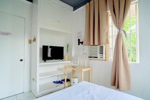 a bedroom with a bed and a tv and a window at Pallet Homes - Landheights Tropics in Iloilo City