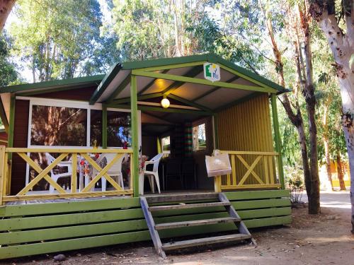 a green cabin with a bench in front of it at Camping Dolce Vita in Calvi