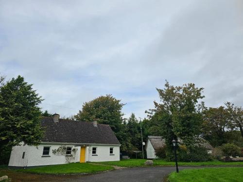 uma casa branca com um telhado preto em Longford Holiday Yellow Star Self-Catering Cottage 