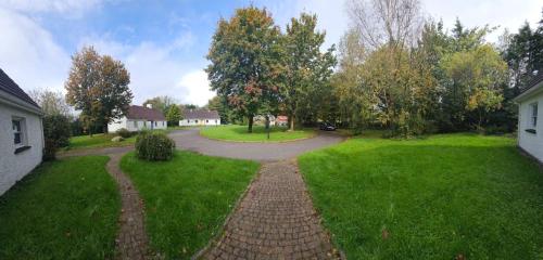 uma passagem de tijolos através de um quintal com árvores e casas em Longford Holiday Yellow Star Self-Catering Cottage 