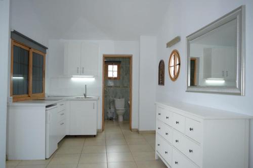 - une cuisine blanche avec un évier et un miroir dans l'établissement Casita Montaña Clara, à Punta de Mujeres