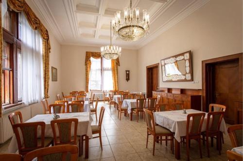 a dining room with tables and chairs and a chandelier at Smolenický zámok in Smolenice