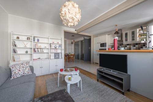 un salon avec un canapé, une télévision et une table dans l'établissement Le Bossuet - Location moyenne durée Lyon 6ème, à Lyon