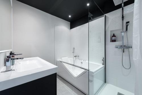 une salle de bain blanche avec un lavabo et une douche dans l'établissement Le Bossuet - Location moyenne durée Lyon 6ème, à Lyon