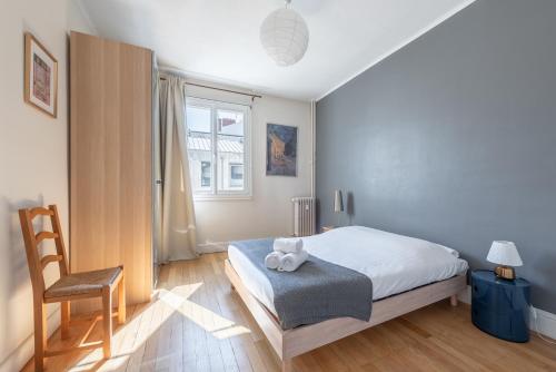une chambre avec un lit, une chaise et une fenêtre dans l'établissement Le Bossuet - Location moyenne durée Lyon 6ème, à Lyon