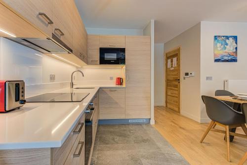 a kitchen with white countertops and a table and chairs at White Pearl A13 - Alpes Travel - Central Chamonix (Sleeps 6) in Chamonix-Mont-Blanc